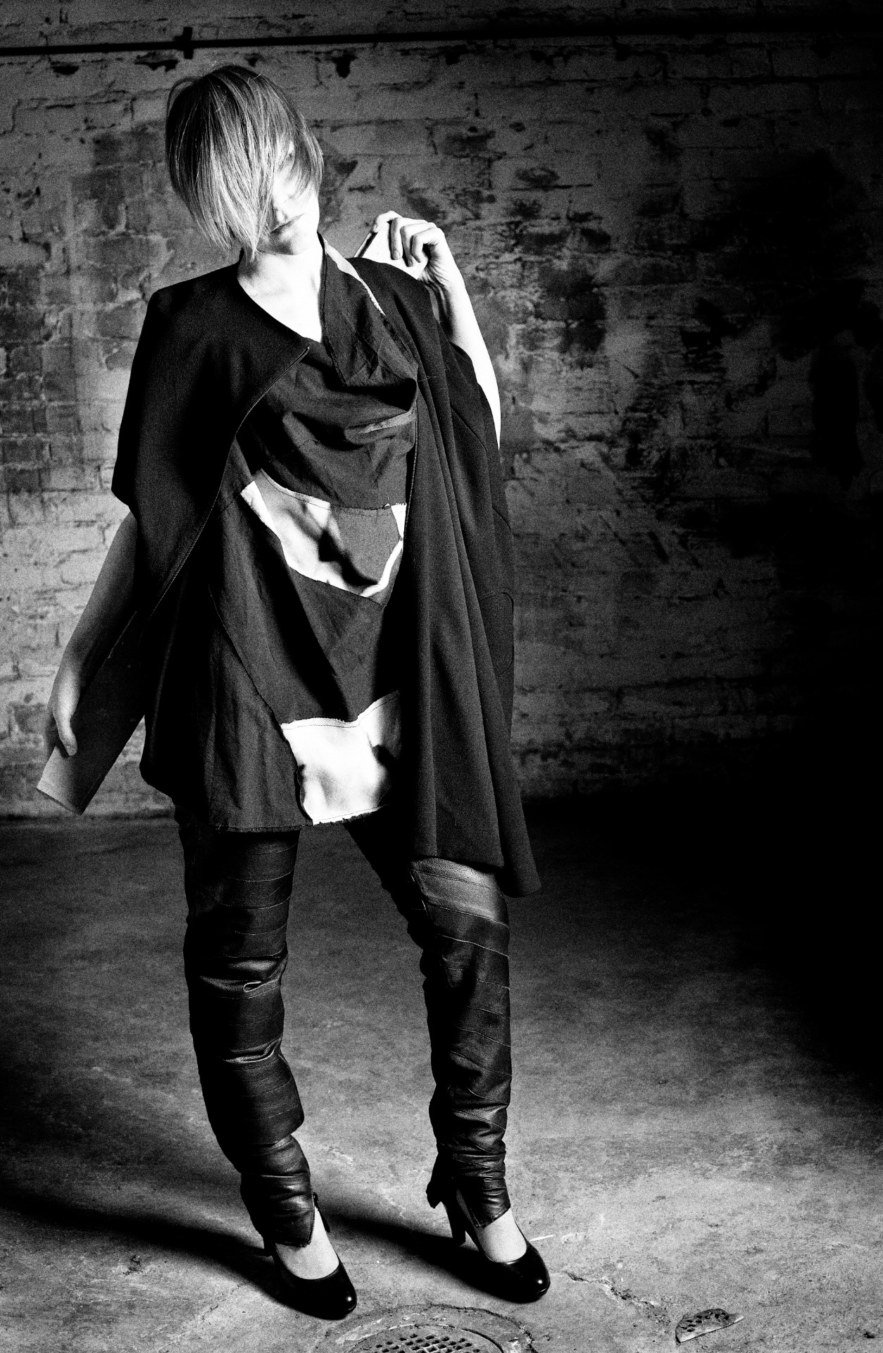 Henkilö seisoo yllään kolmiosainen asu: villakrepistä valmistettu jakku, nahkahousut ja ylijäämäpaloista koottu toppi, jokainen vaate on yhdestä kappaleesta rakennettu.